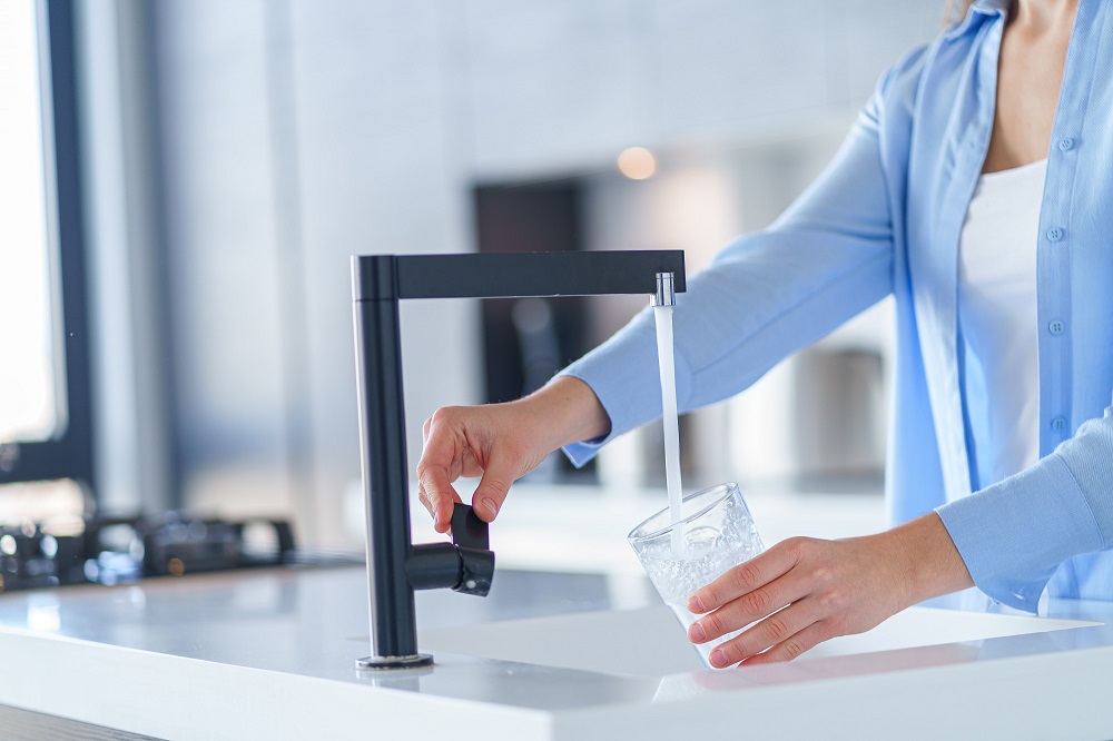 The image of a person filling a glass of water. This image was used in a news titled "The best home water purifier in the Iranian market" on the website irotime.com.